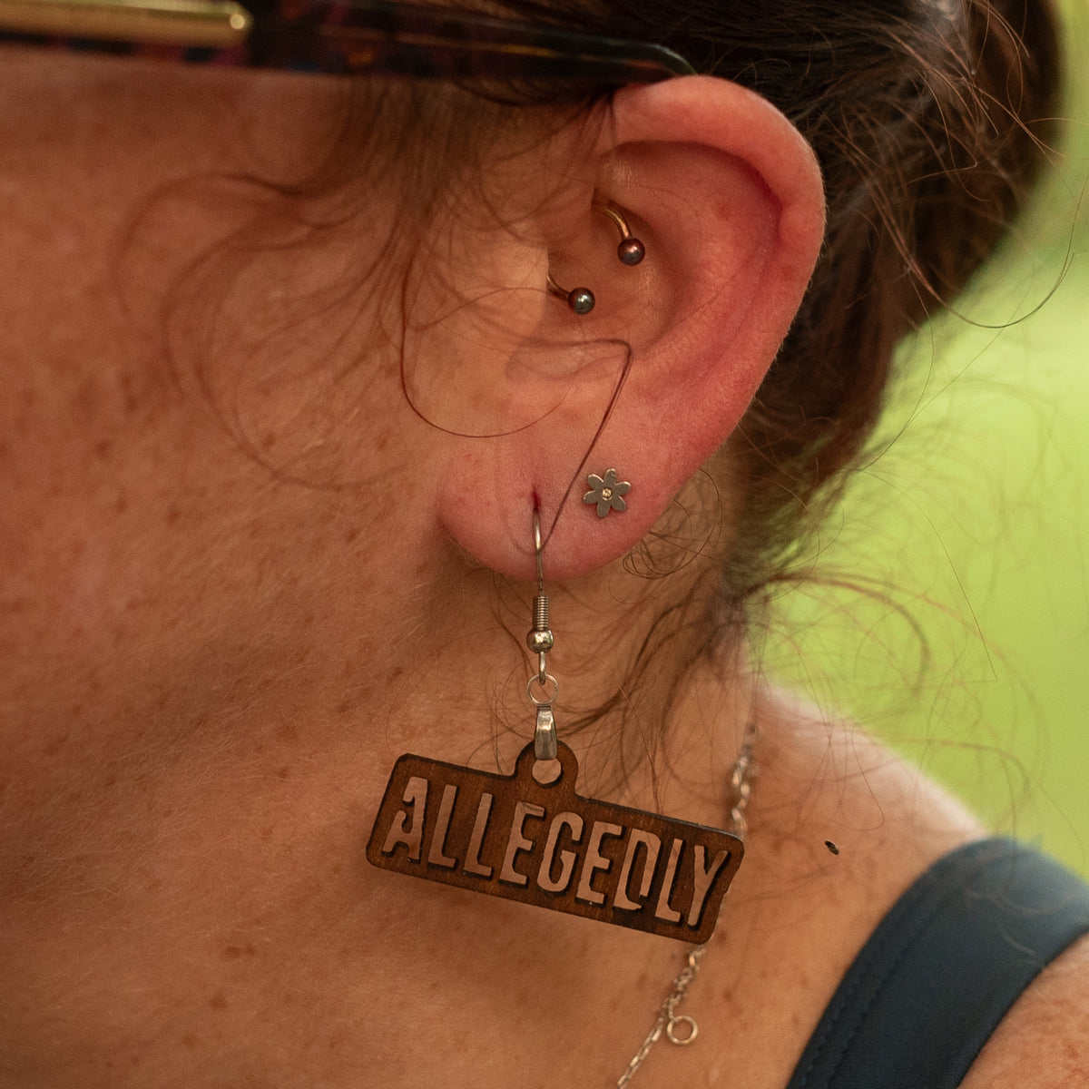 Allegedly laser-cut wood earring shown being worn, with a stainless steel ear wire.